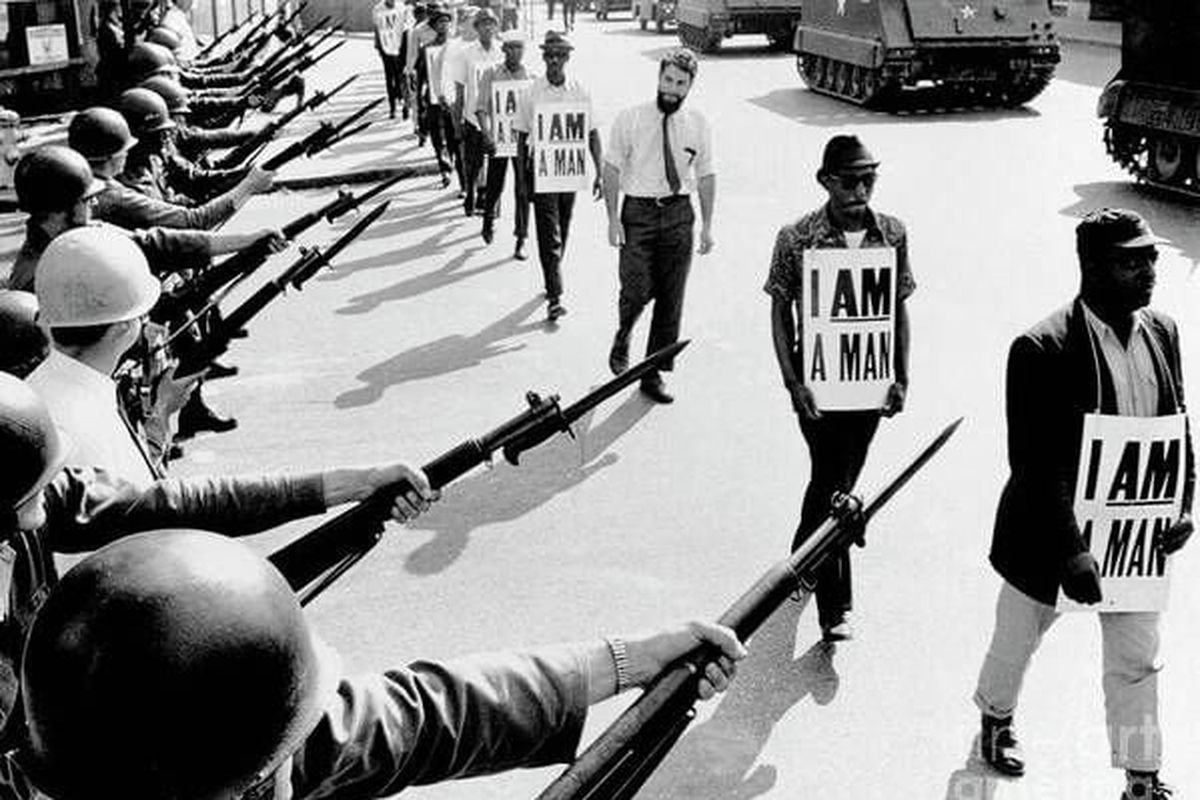 Civil Rights activists are blocked by National Guardsmen brandishing bayonets while trying to stage a protest on Beale Street in Memphis, Tenn. The marching demonstrators, who are wearing signs which say “I Am A Man,” are also flanked by tanks. The Rev. Dr. Kenneth Davis is second from right. (Getty Images)